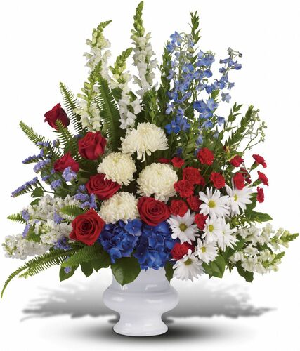 With Distinction showcases  beautiful mix of all-American red, white and blue flowers such as hydrangea, roses, miniature carnations, snapdragons, chrysanthemums and more are perfectly arranged in a white urn in Washington DC and Rockville MD, Palace Florists